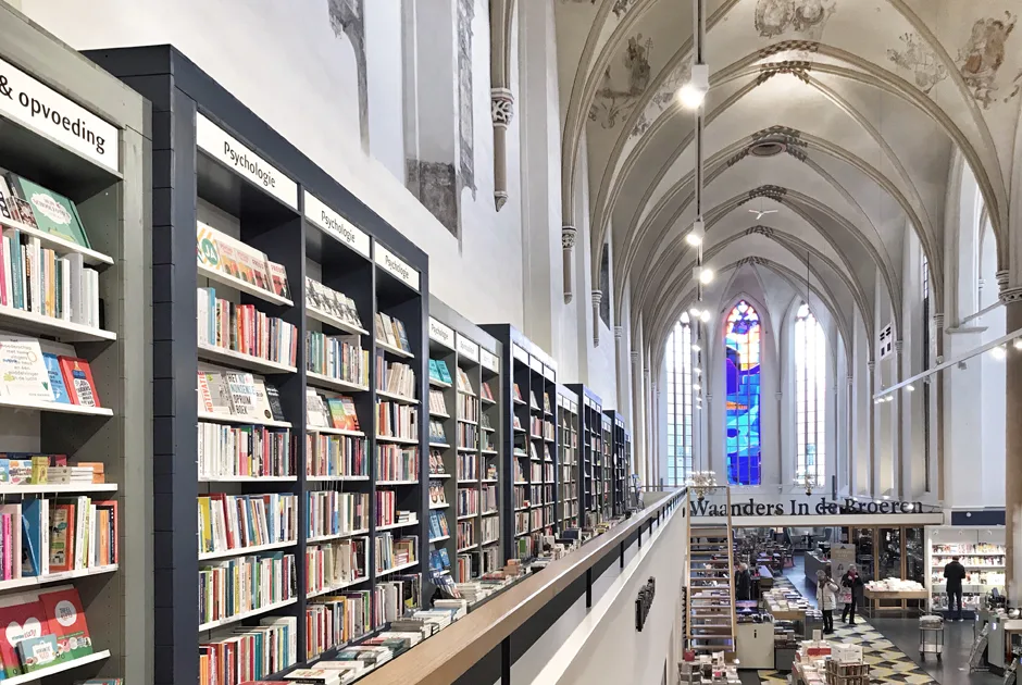 Boekwinkel in een kerk met hoge boekenkasten en glas-in-loodramen